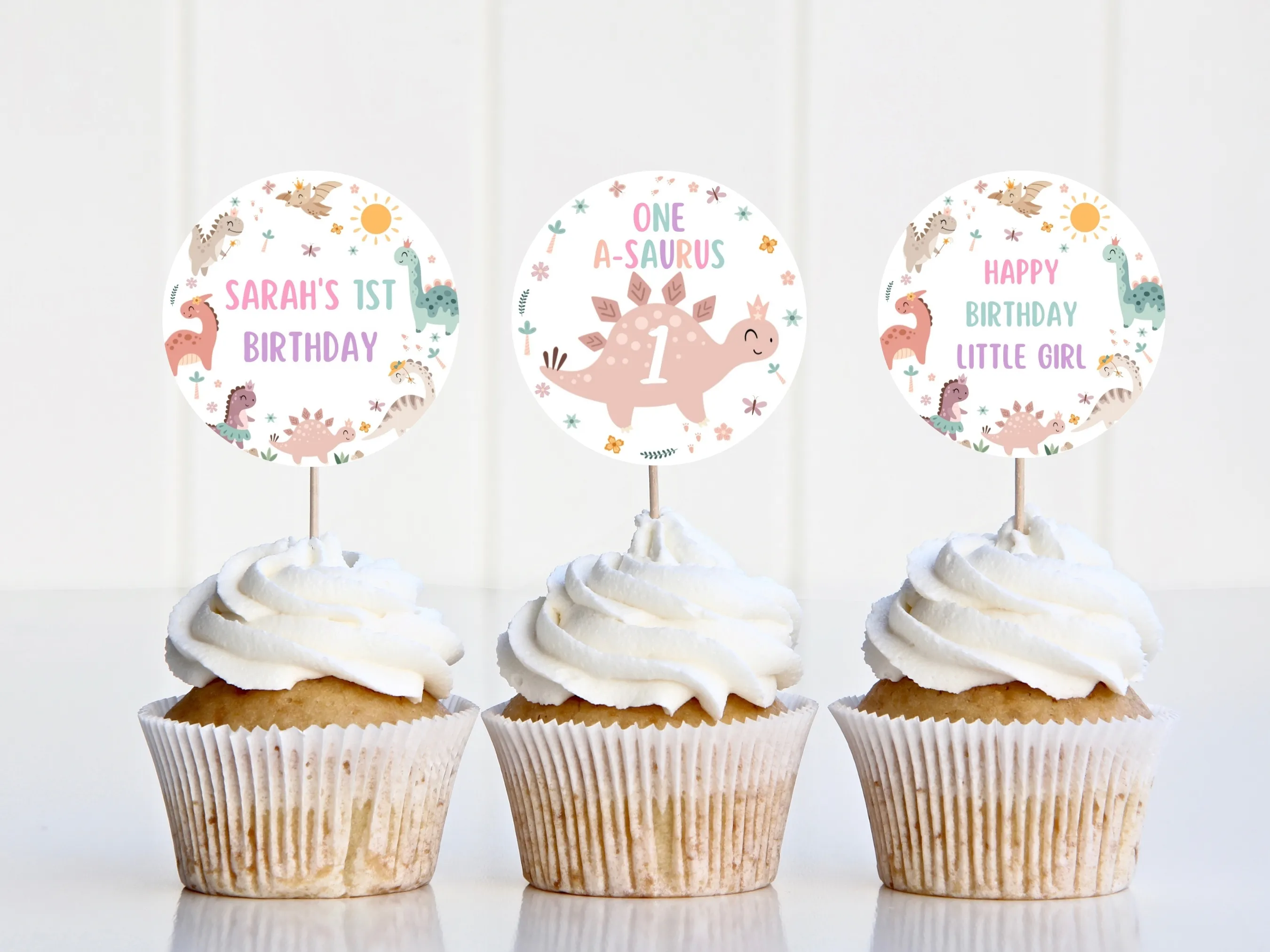 Baby girl dinosaur cupcake toppers with cute pink dino theme and “One” cake topper for first birthdays, editable Canva template by fllcdesigns